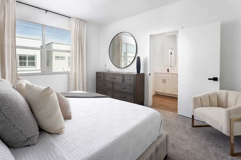 a bedroom with a large bed and a dresser with a mirror