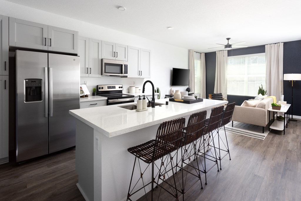 an open concept kitchen and living room with a large white island with a white countertop and