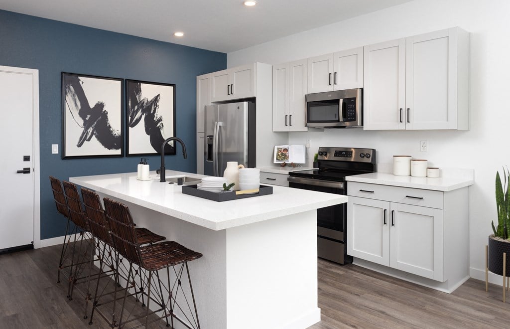 a kitchen with white cabinetry and a large white island with a white countertop and black