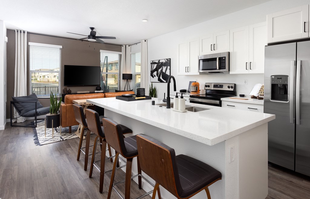 an open concept kitchen and living room with a large white island with a white countertop and