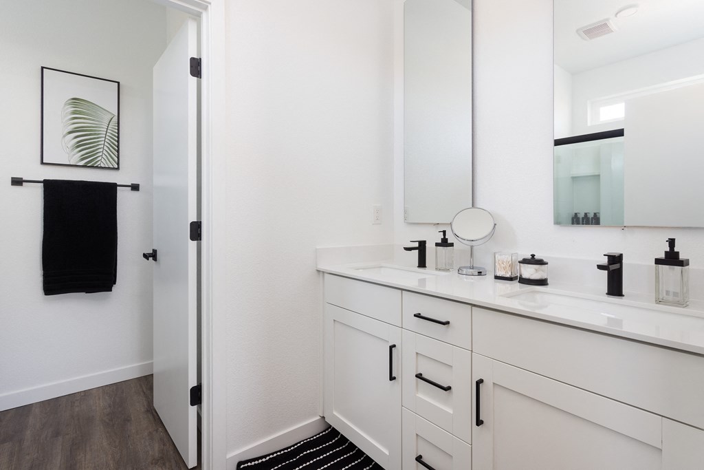 a bathroom with white cabinets and a black rug