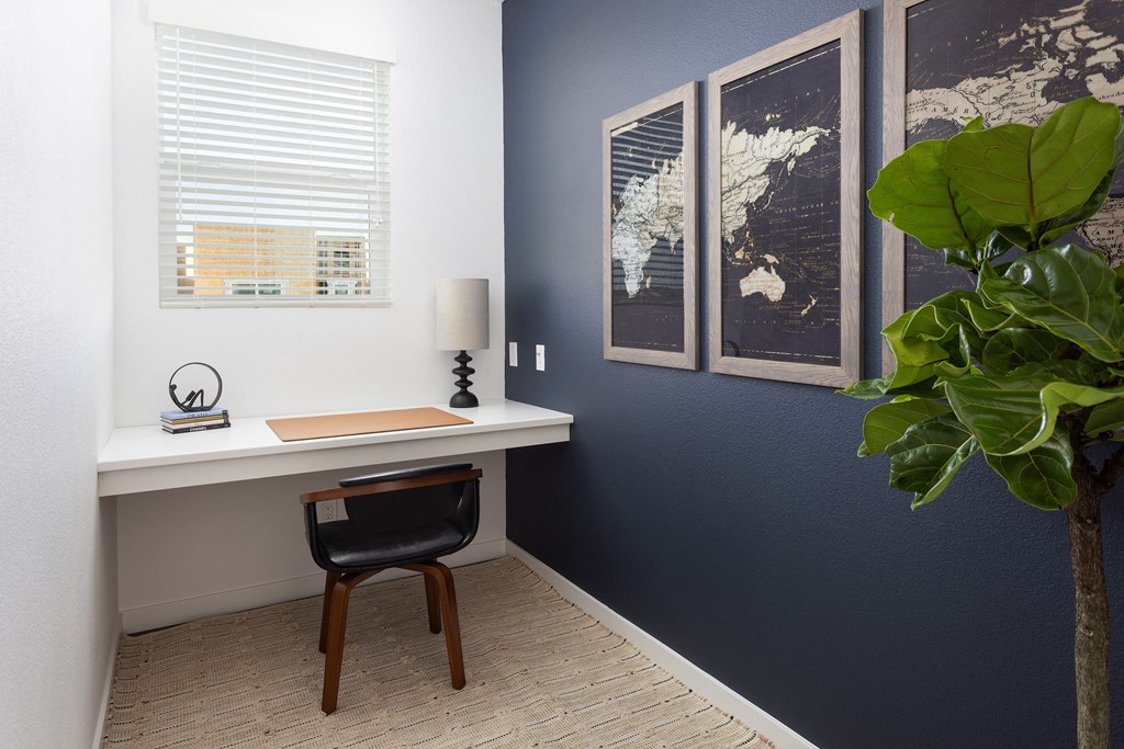a desk with a chair and a lamp in a room with a blue wall
