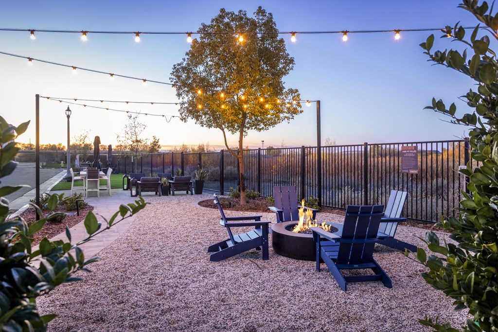 a patio with chairs and a fire pit and lights
