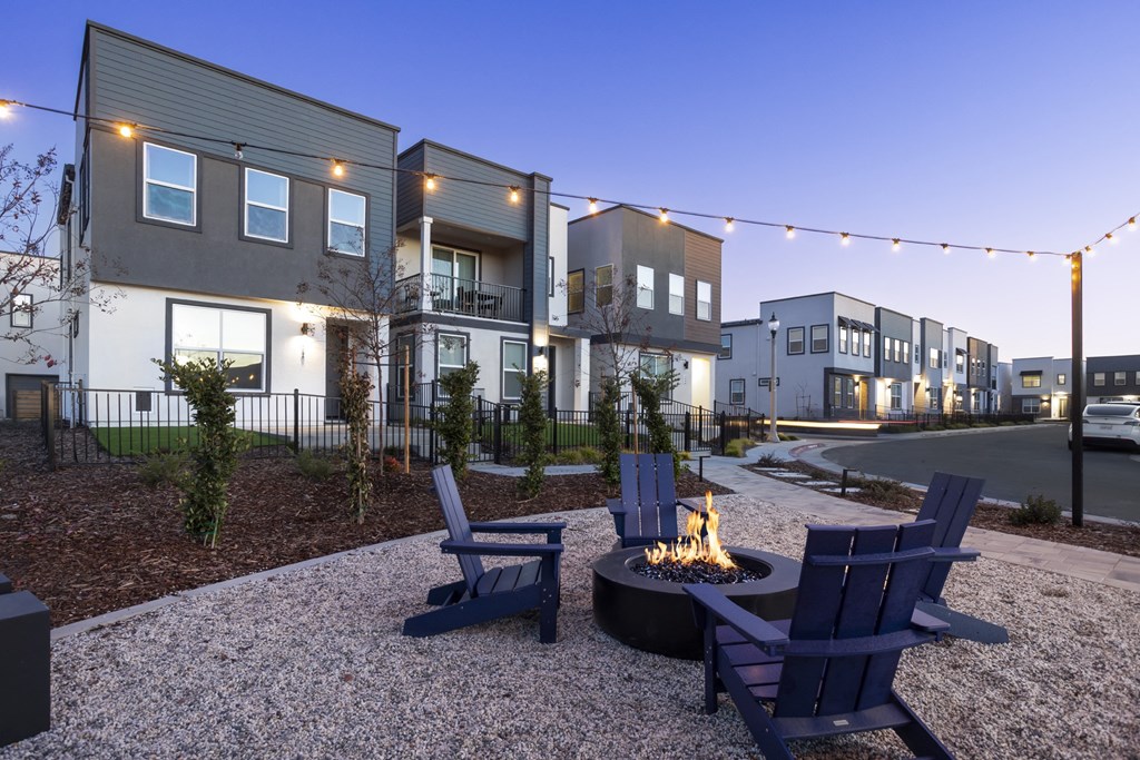 an outdoor patio with chairs and a fire pit at dusk