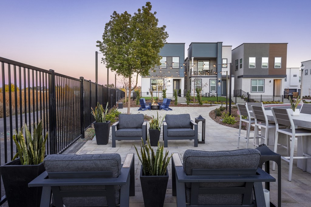 a rendering of a patio with chairs and tables in front of apartments