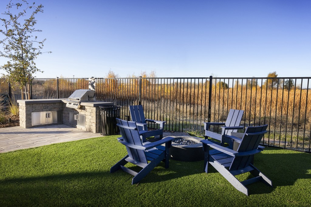 a backyard with two blue chairs and a fire pit and a fence