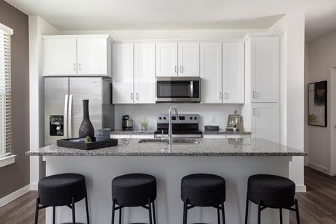 A kitchen with white cabinets and a marble countertop.