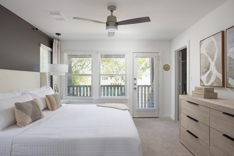 A bedroom with a large bed and a ceiling fan.