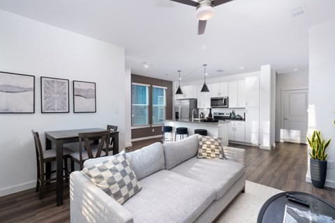 A modern living room with a grey couch and a dining table.