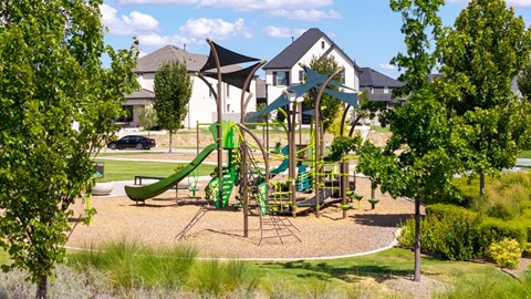 A playground with a green slide and a brown swing set.