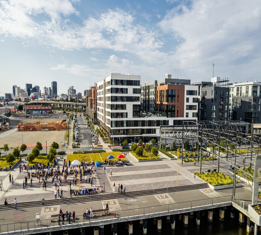 people walking on a bridge over a city street with buildings