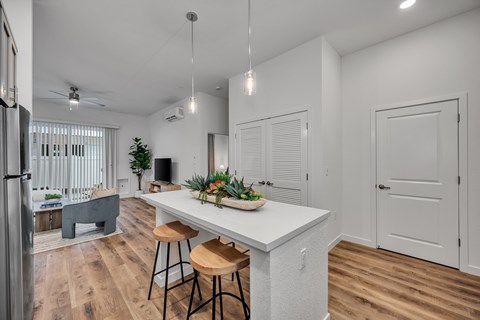 A kitchen with a white counter and bar stools.
