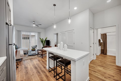 A kitchen with a white counter and wooden floors.