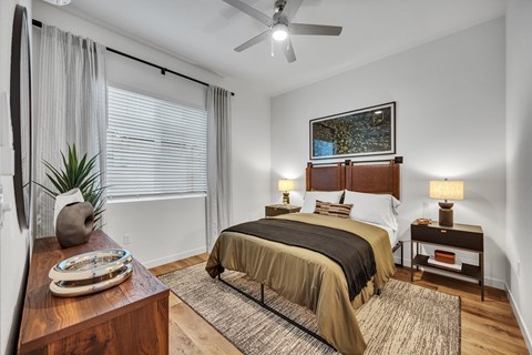 Bedroom with tan bedding and wood furnishings at Estia Roseville Apartments, Roseville, 95747