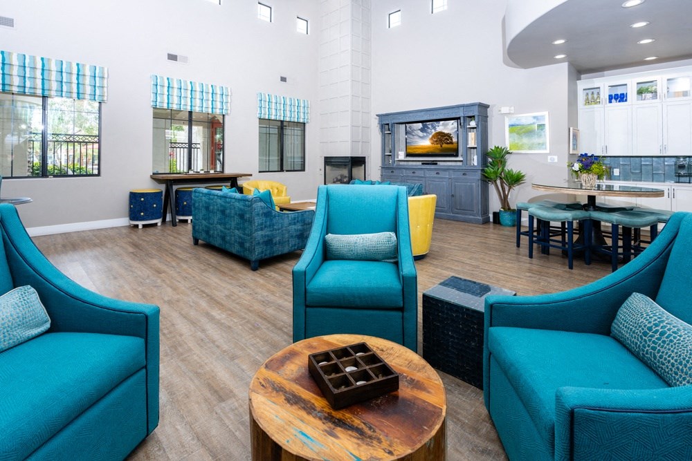 a lounge area with blue chairs and a table with a fireplace