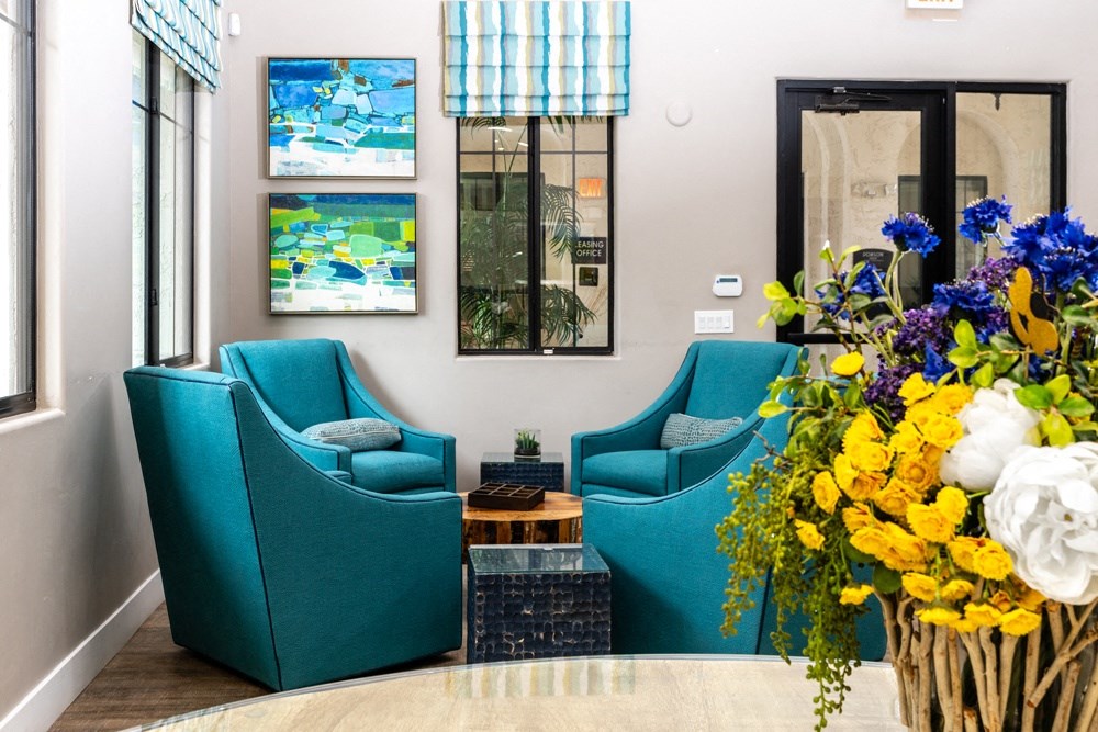 a living room with blue chairs and a vase of flowers