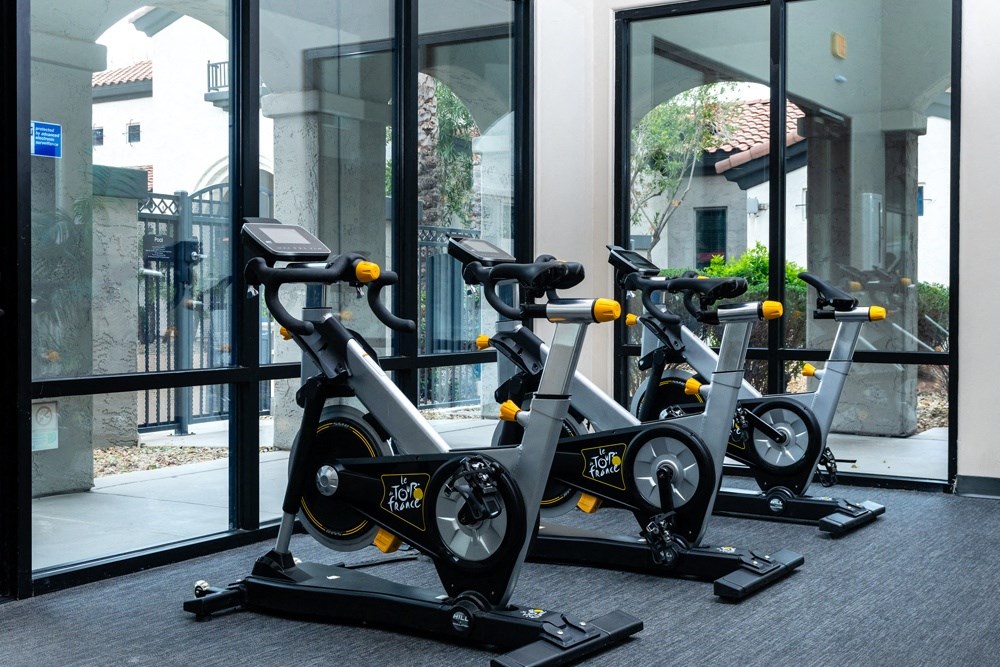 three spin bikes in front of a window in a gym