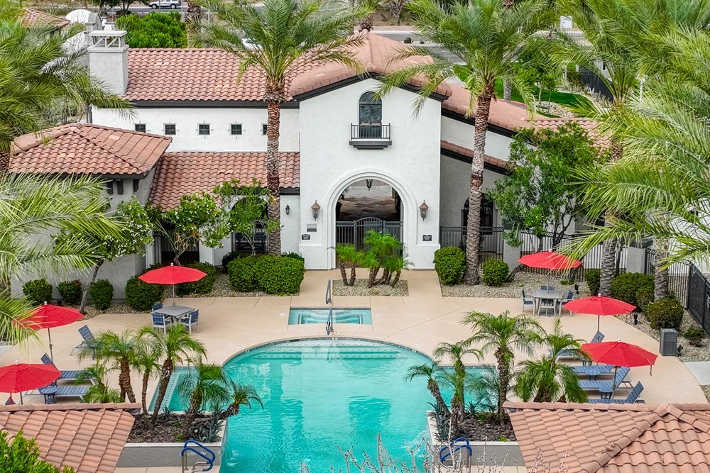 a swimming pool in front of a house with palm trees