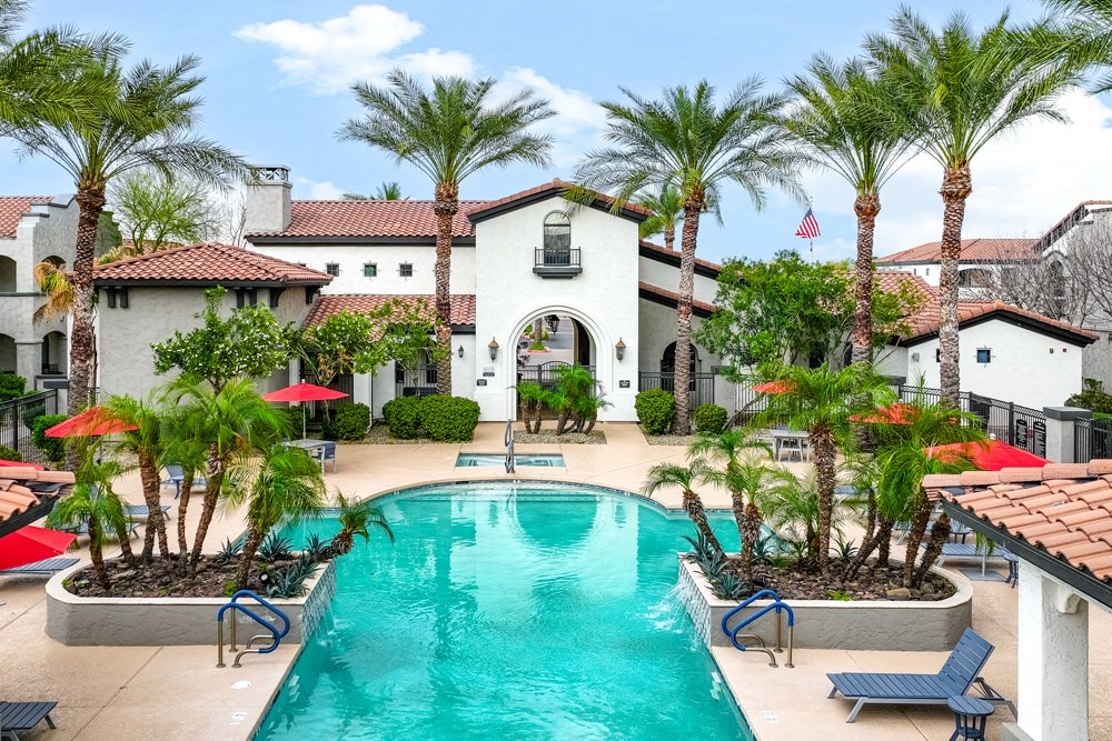 a large swimming pool in front of a house with palm trees