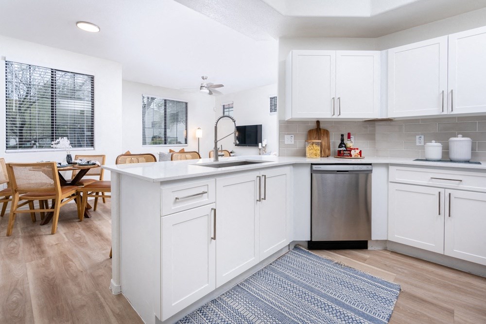a kitchen with white cabinets and a white counter top and a stainless steel sink