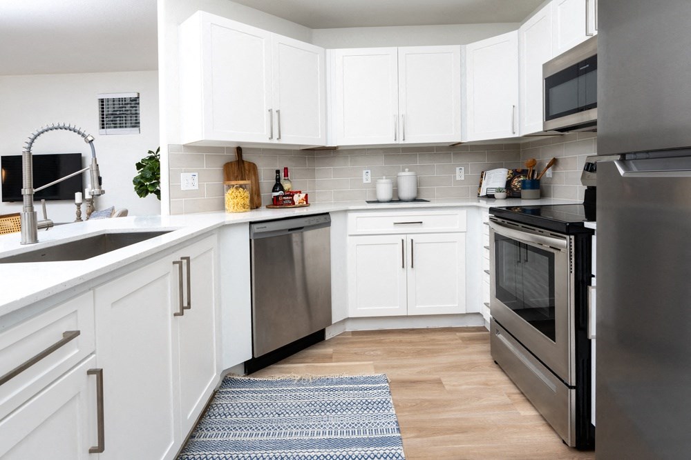 a white kitchen with stainless steel appliances and white cabinets
