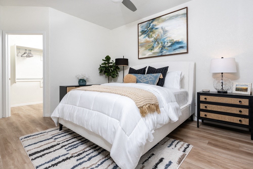 a bedroom with a white bed and a painting on the wall
