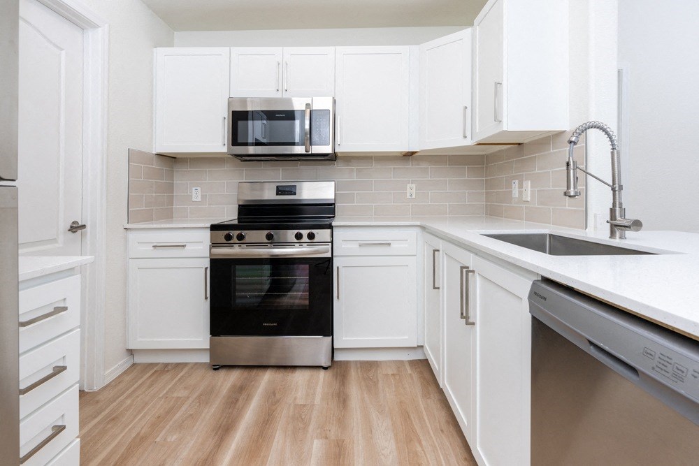 a white kitchen with stainless steel appliances and white cabinets