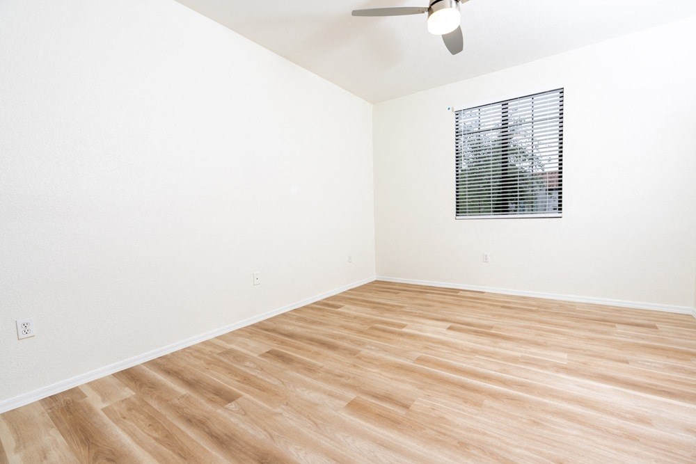 an empty room with wood flooring and a window