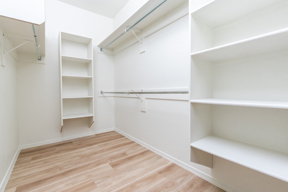 a walk in closet with shelves and a wood floor