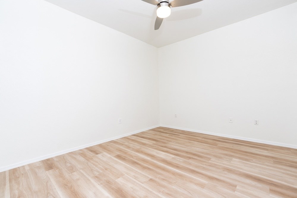 an empty room with wooden floors and a ceiling fan