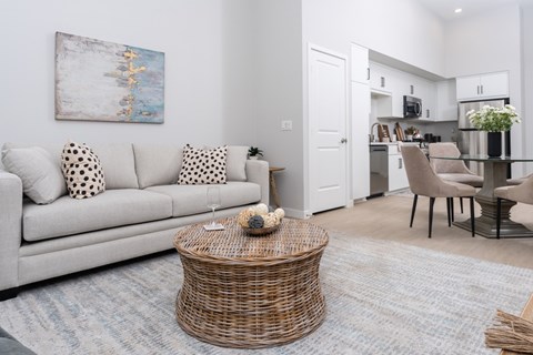A living room with a grey couch and a wicker coffee table.