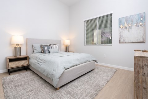 2-Bedroom Luxury Apartments in Ontario, CA - Downtown Ontario Luxury Apartments - Bedroom With Matching Nightstand, A Window, Wall Art, And A Wooden Dresser.