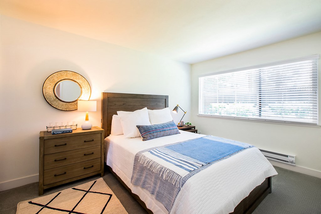 A bedroom with a bed, nightstand, and window.