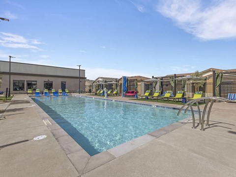 A large outdoor swimming pool with lounge chairs and a building in the background.