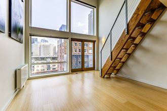 Downtown Seattle Lofts For Rent - Huge Living Room With Vaulted Ceilings, Floor-To-Ceiling Windows, City Views, And Staircase.