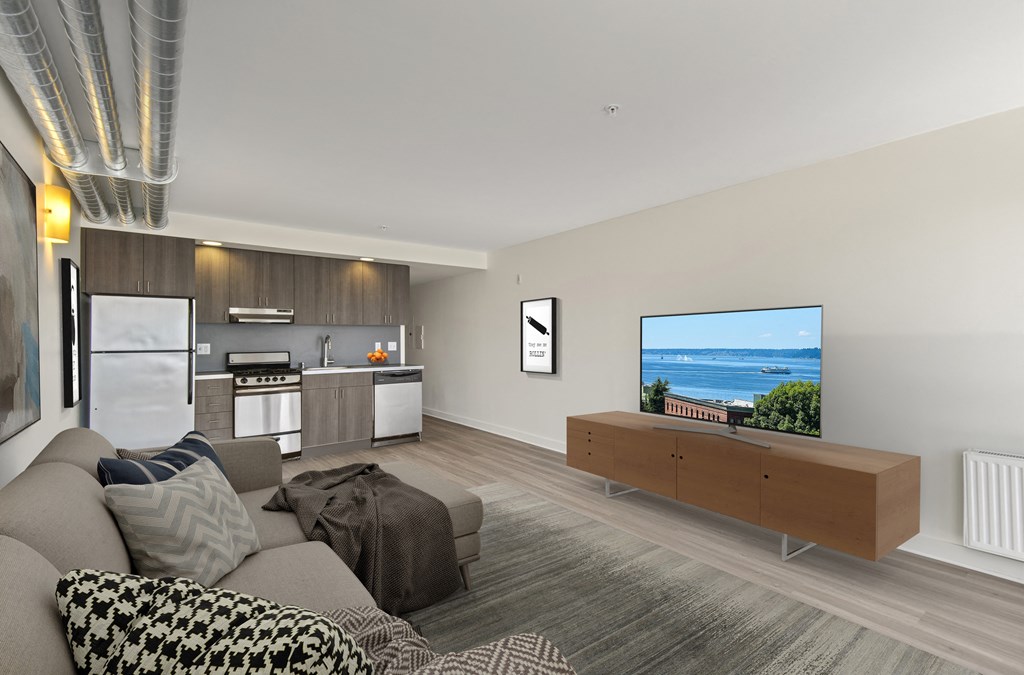 a living room with a large tv and a kitchen in the background