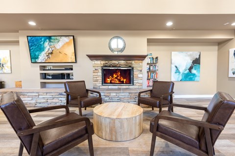 A living room with a stone fireplace and a television mounted on the wall.