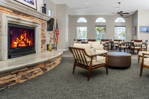 a room with a fireplace and a table and chairs at 55+ FountainGlen Valencia, California