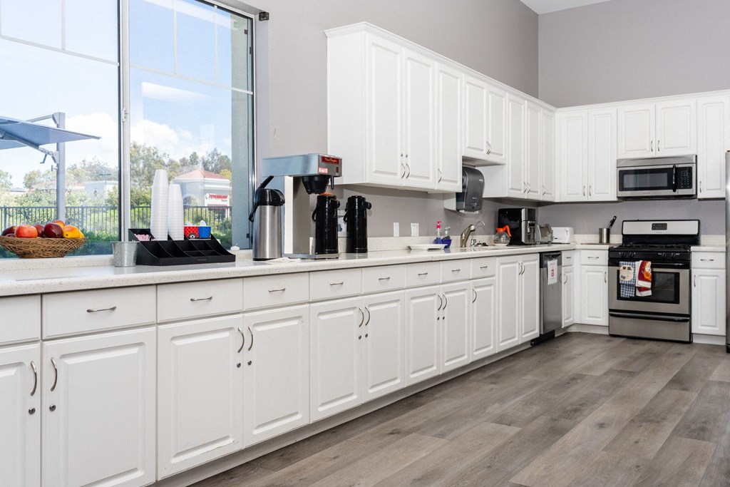 a large kitchen with white cabinets and a large window