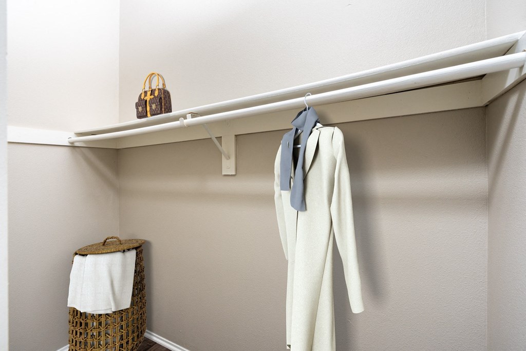a walk in closet with a white robe hanging on a rail and a white towel