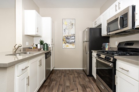 a kitchen with stainless steel appliances and white cabinets at 55+ FountainGlen Valencia, Valencia, California