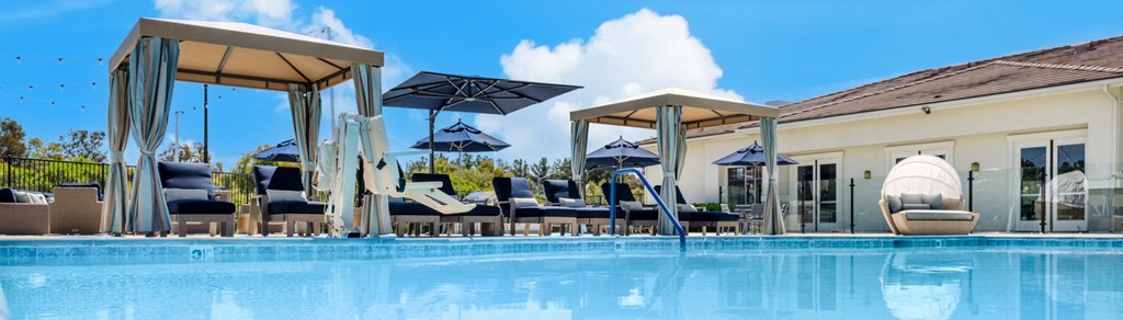 a swimming pool with chairs and umbrellas a swimming pool with chairs and umbrellas at 55+ FountainGlen Valencia, Valencia, California