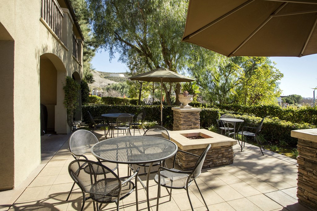 a patio with a table and chairs and a fire pit at 55+ Remington at Ladera Ranch, California, 92694