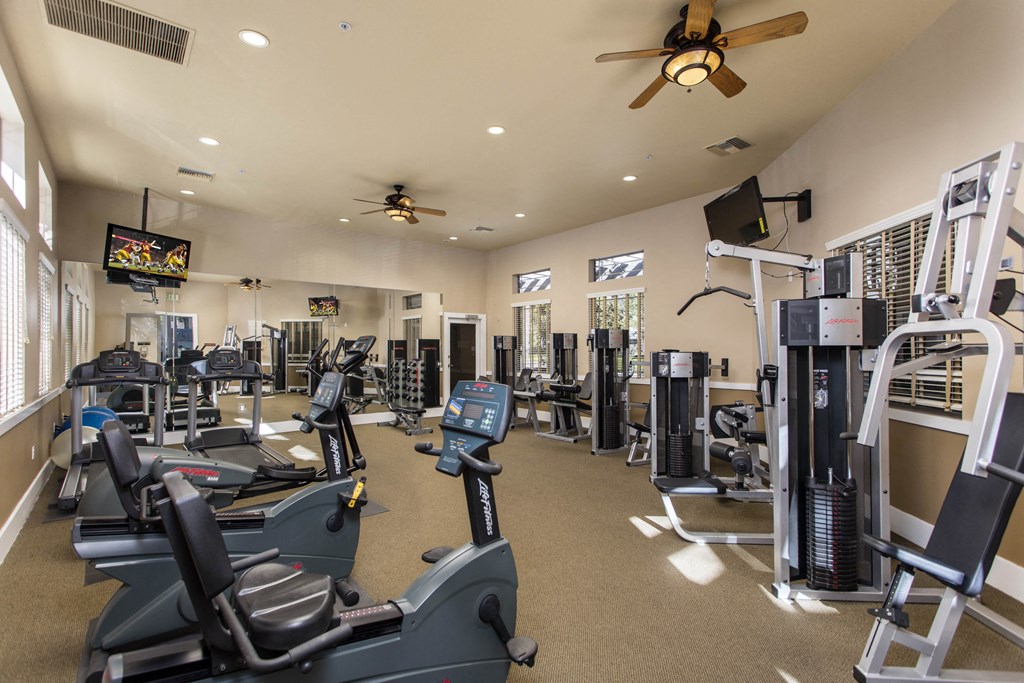 a spacious fitness center with cardio equipment and a flat screen tv at 55+ Remington at Ladera Ranch, California, 92694