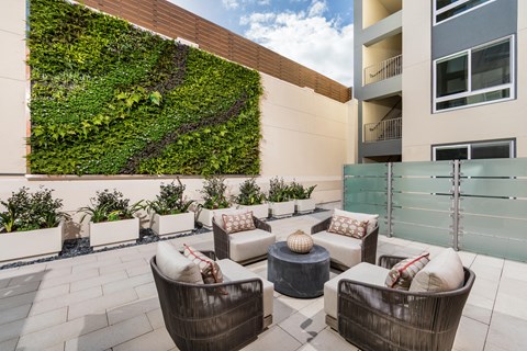 a living wall on the side of a building with patio furniture
