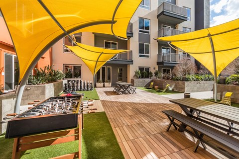 a patio with picnic tables and umbrellas and a barbecue grill