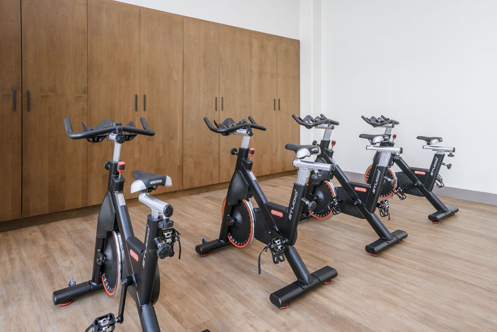 a group of exercise bikes in a room with wooden floors