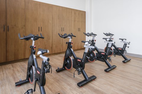 a group of exercise bikes in a room with wooden floors