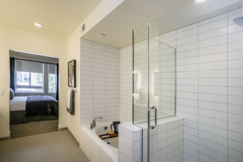 a bathroom with white tile walls and a shower and a bed