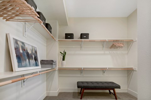 a closet with shelves and a bench and a painting on the wall
